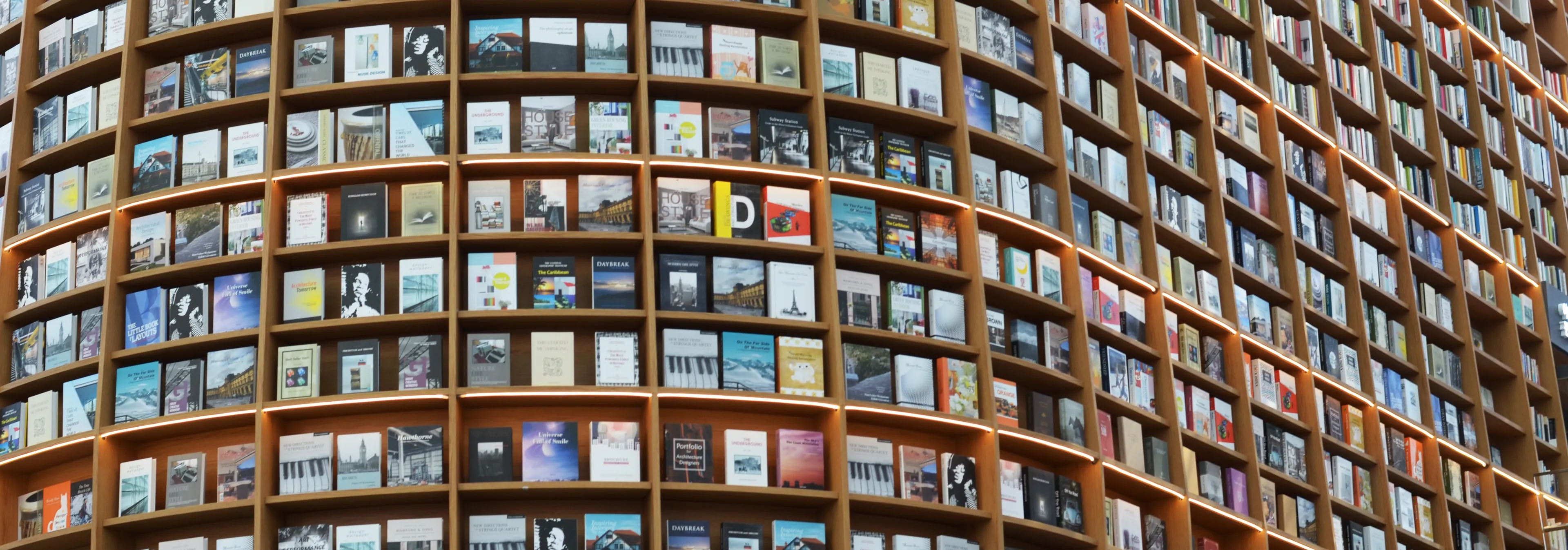 Rundes Bibliotheksregal mit unzähligen bunten Büchern, sinnbildlich für die Vielfalt professioneller Buchproduktion